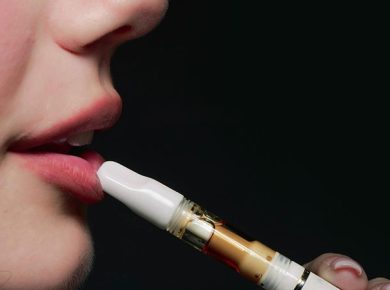 woman holding an e-cigarette that touches her lips